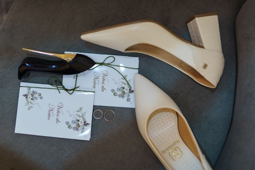Sapatos, convite e alianças dispostos como detalhe do casamento