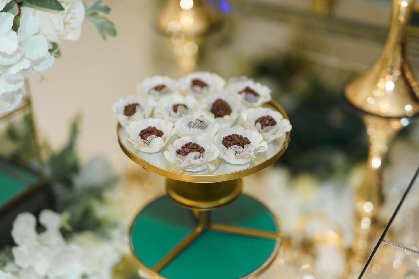 Doces finos servidos em prato dourado na mesa de doces do Estrela Buffet