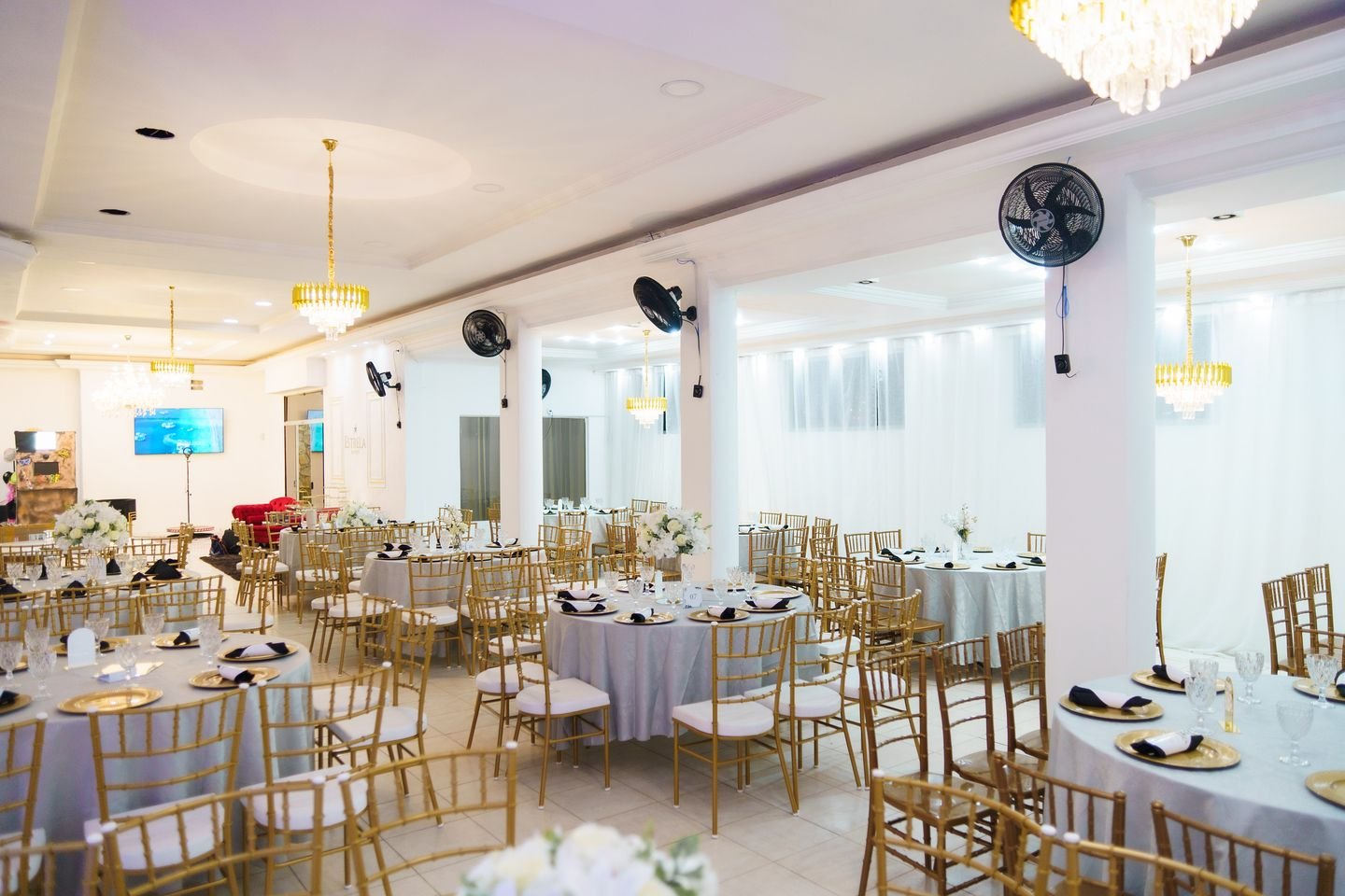 Salão do Estrela Buffet montado com mesas redondas, cadeiras douradas e lustres de cristal
