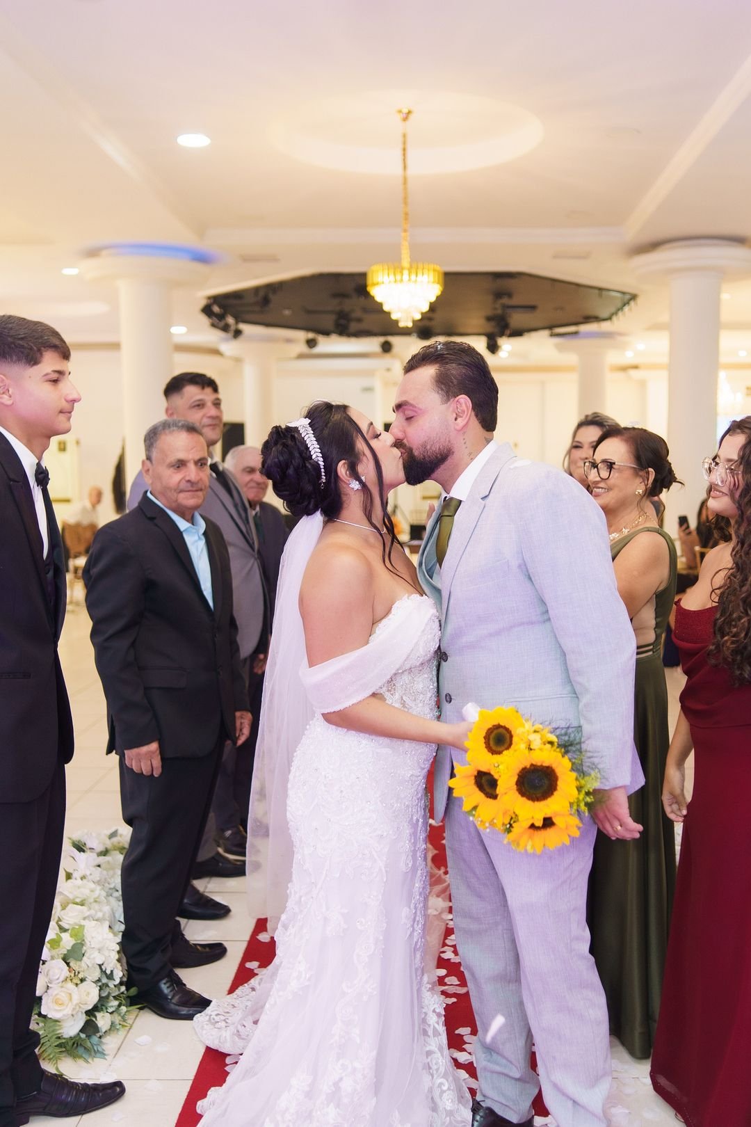 Noivos se beijando cercados pelos convidados no salão do Estrela Buffet