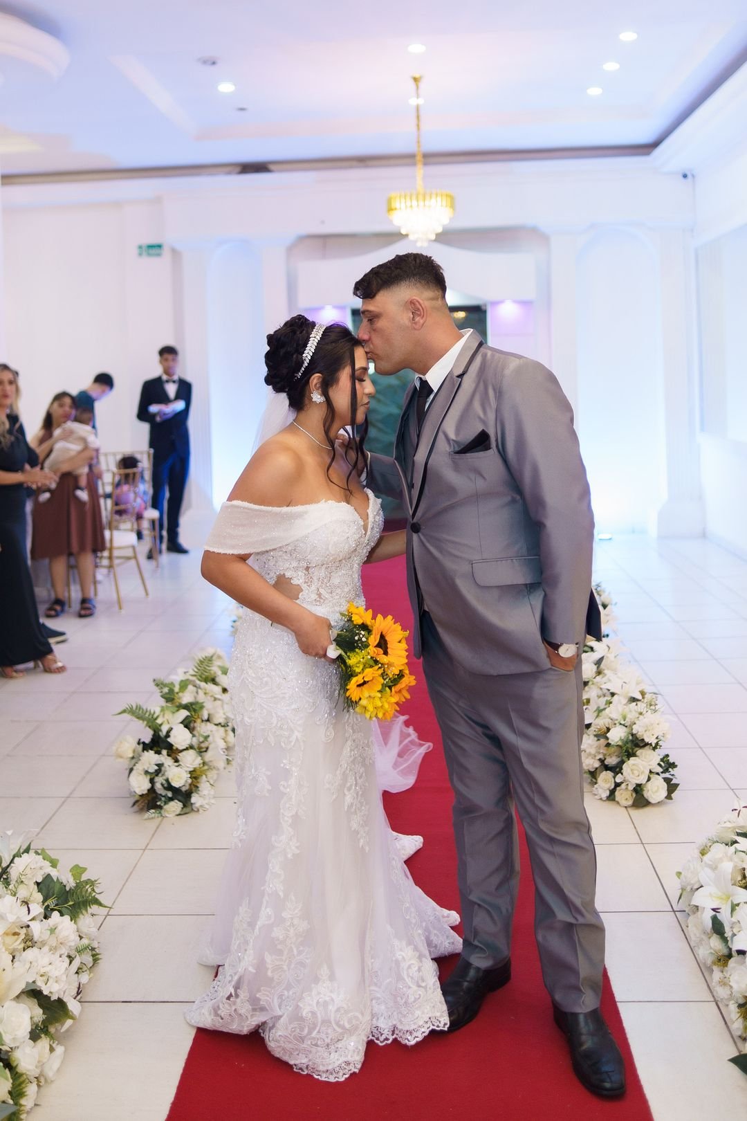 Noivos se beijando no corredor do salão logo após a cerimônia