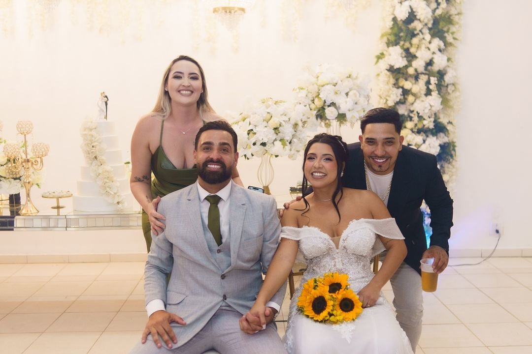 Noivos ao lado da família diante do painel de flores