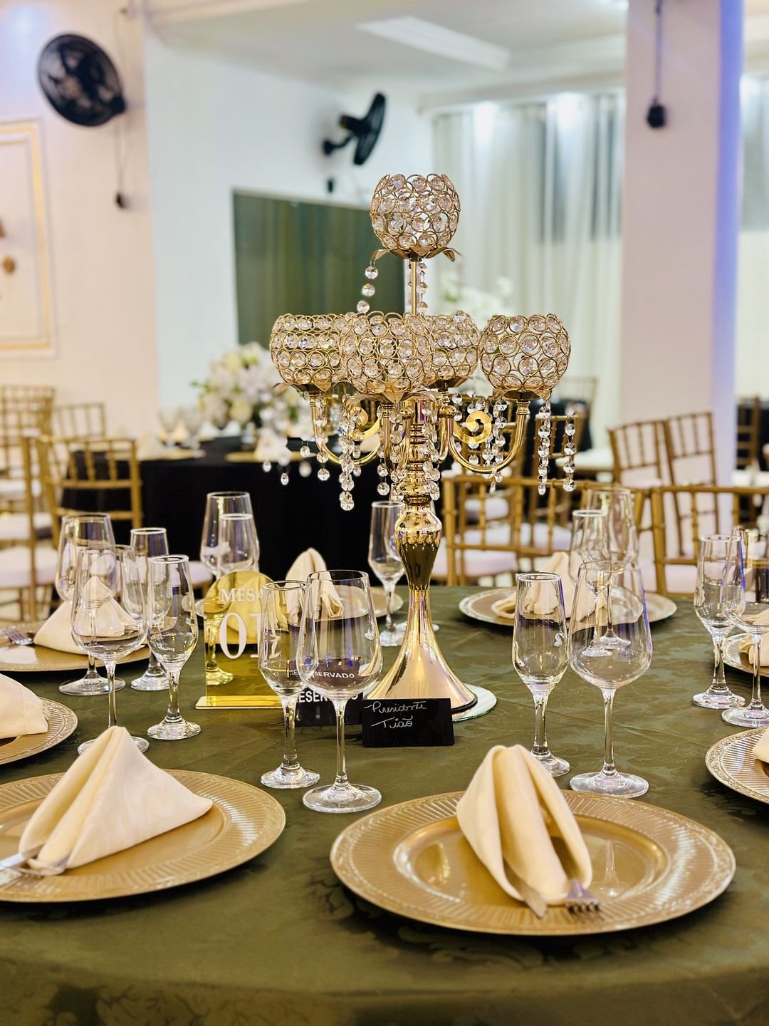 Mesa posta para evento corporativo no Estrela Buffet, com sousplat dourado e taças de cristal
